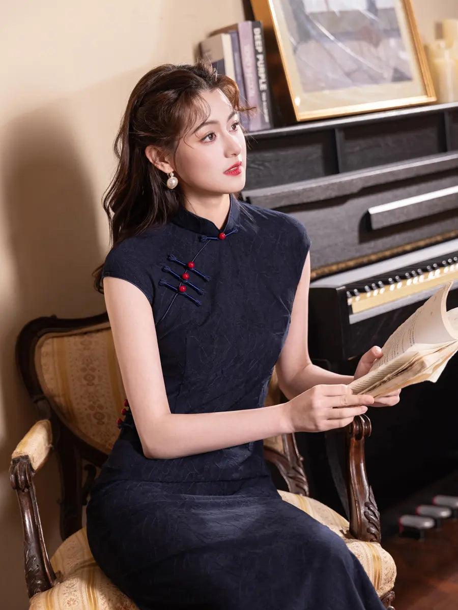 Woman in a dark Vintage Navy Blue Jacquard  Sleeveless Qipao Dress With Red Buttons sitting in front of a piano, holding a book.