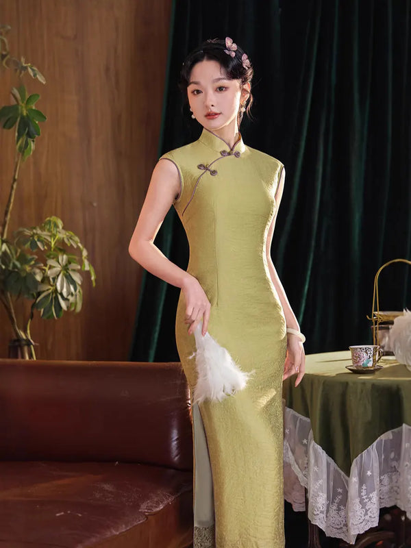 Woman in a green traditional Chinese Vintage Olive Green Long Sleeveless Qipao dress standing in a room with a table and plants.
