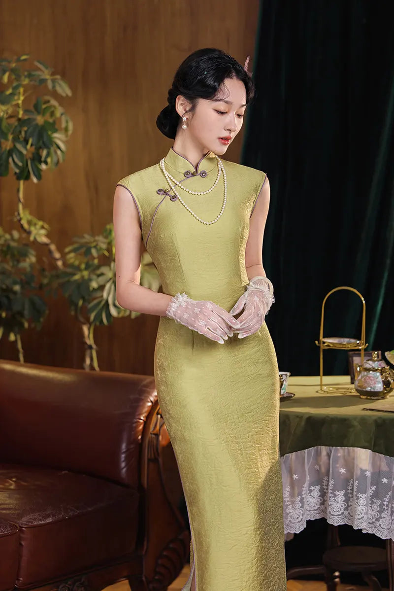Woman in a chinese Olive Green Long Sleeveless Qipao with gloves standing in an elegant room.