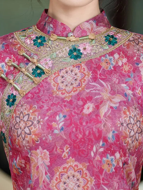 A close-up of a pink floral traditional Chinese cheongsam jacket with embroidered details, gold trim, and wooden frog closures.