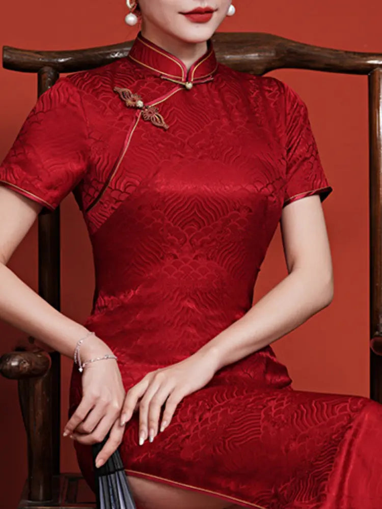 Woman wearing a traditional  Vintage Red  Short Sleeve Mulberry Silk Jacquard Qipaodress sitting on a wooden chair against a red background