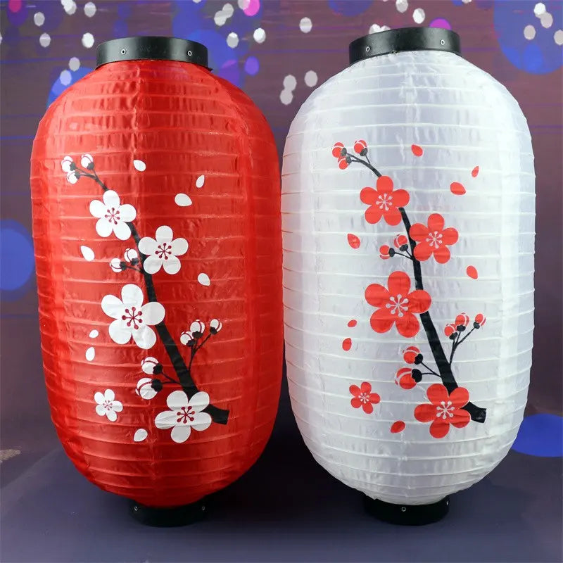 Two decorative chinese lanterns, one red and one white, with floral designs on a blurred background.