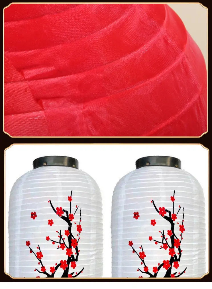 Two white lanterns with black floral designs on a red fabric background