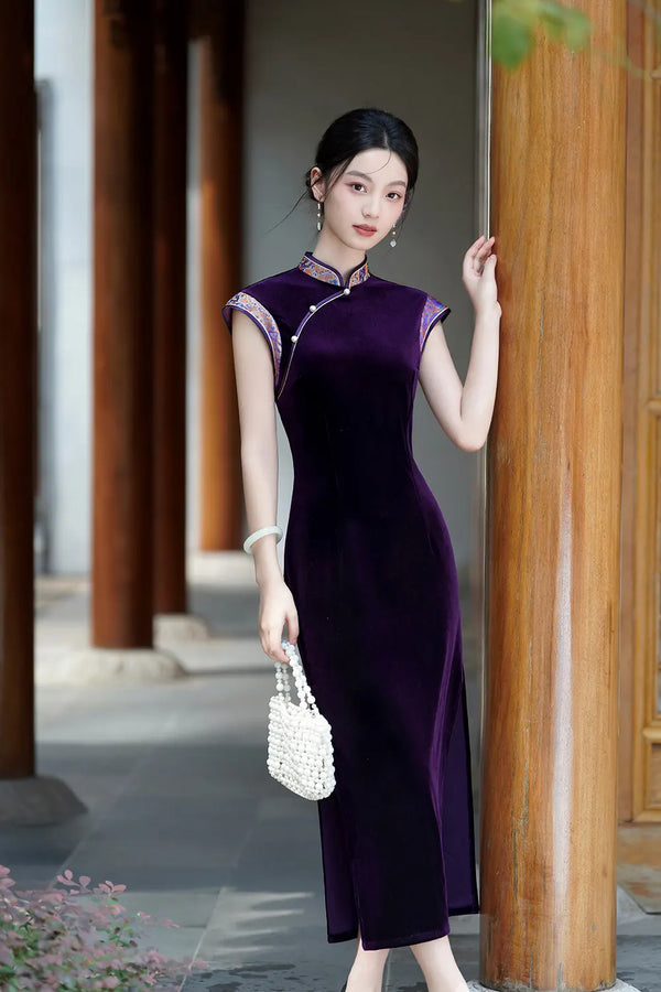 Woman in a Violet Velvet Qipao Cheongsam Dress with Floral Trim standing against a wooden pillar outdoors.