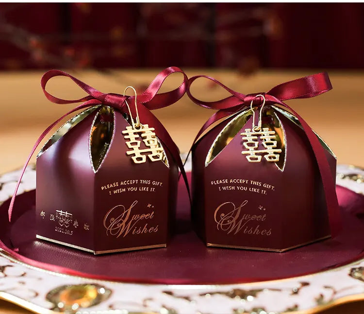 Two maroon gift boxes with gold ribbons and 'Sweet Wishes' text on a decorative plate.