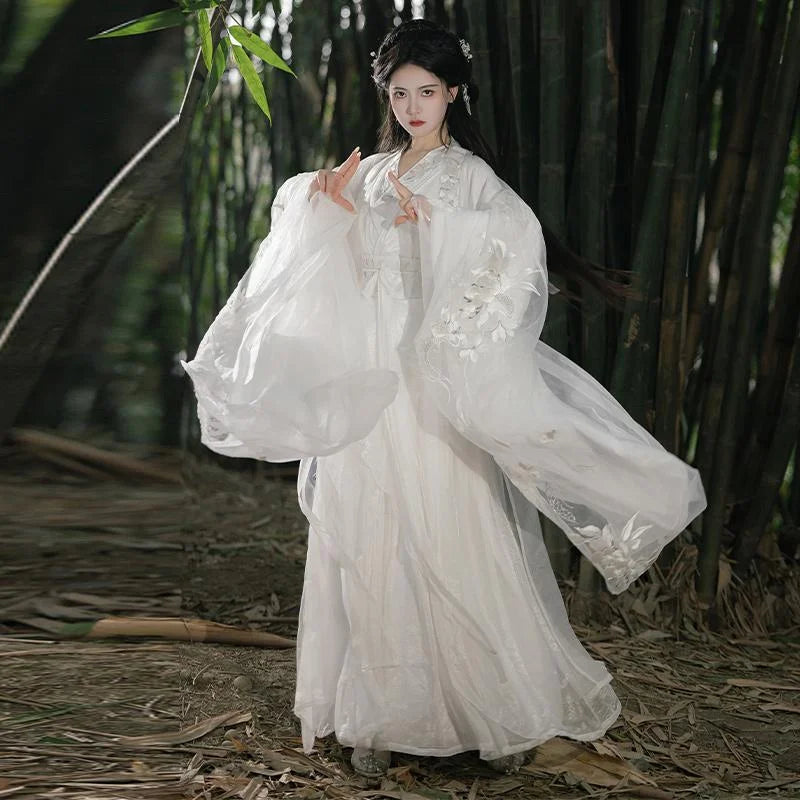 Person in a white traditional chinese outfit  Song Dynasty Hanfu Dress standing in a natural setting with bamboo