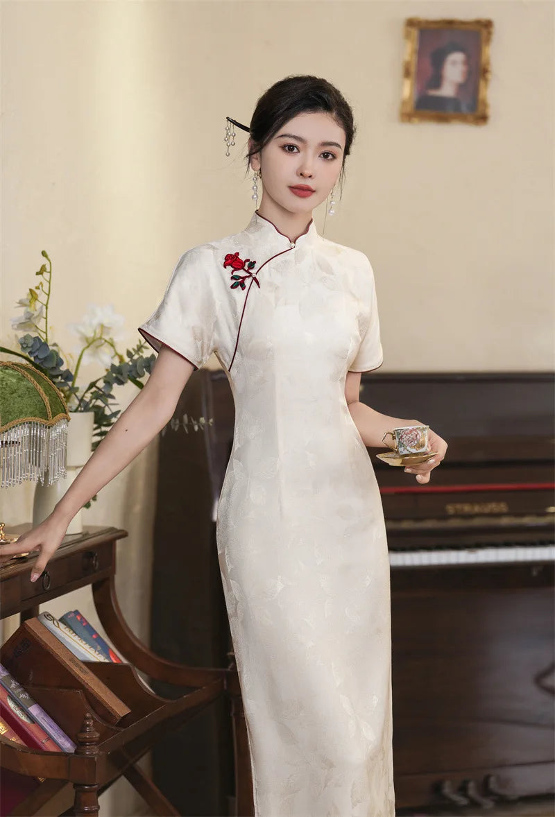 Woman in a  traditional White Jacquard Qipao Cheongsam Dress With Red Trim with red floral embroidery in a vintage room.