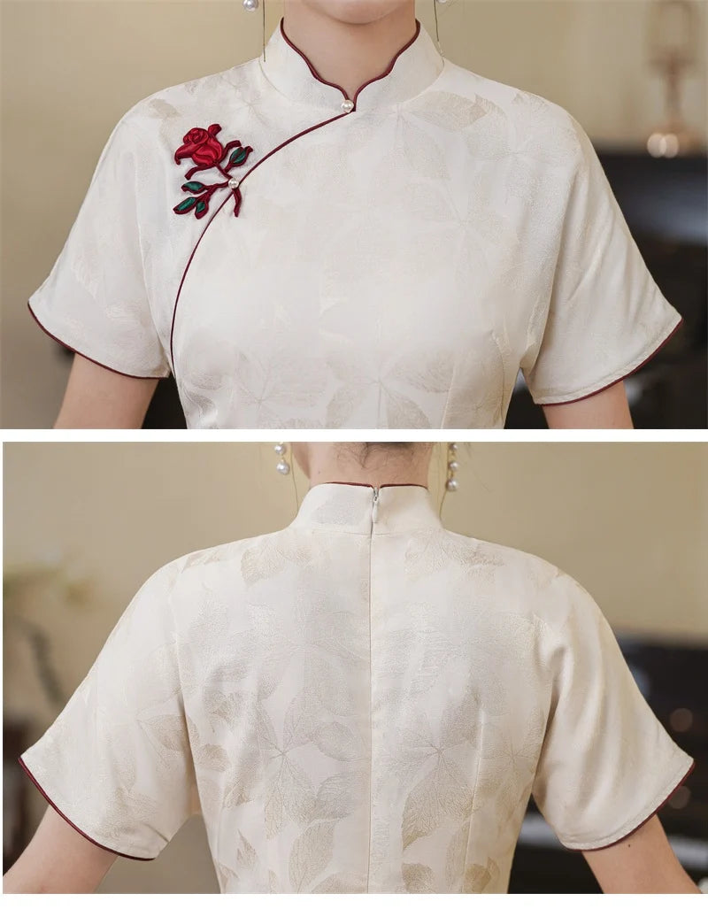 White traditional outfit with red floral embroidery on a neutral background