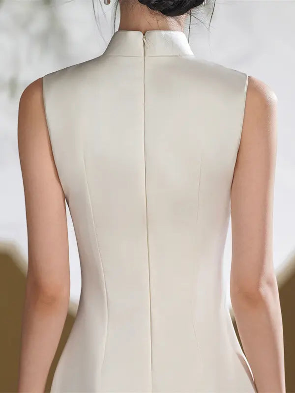 Rear view of a woman wearing a sleeveless high-neck dress in a warm off-white or cream shade, showing the center back seam and zipper closure.