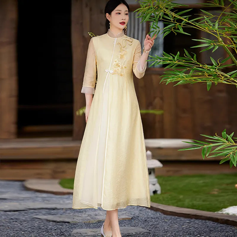 Woman in a Floral Embroidered Loose A line yellow Cheongsam Qipao Dress standing outdoors with greenery in the background
