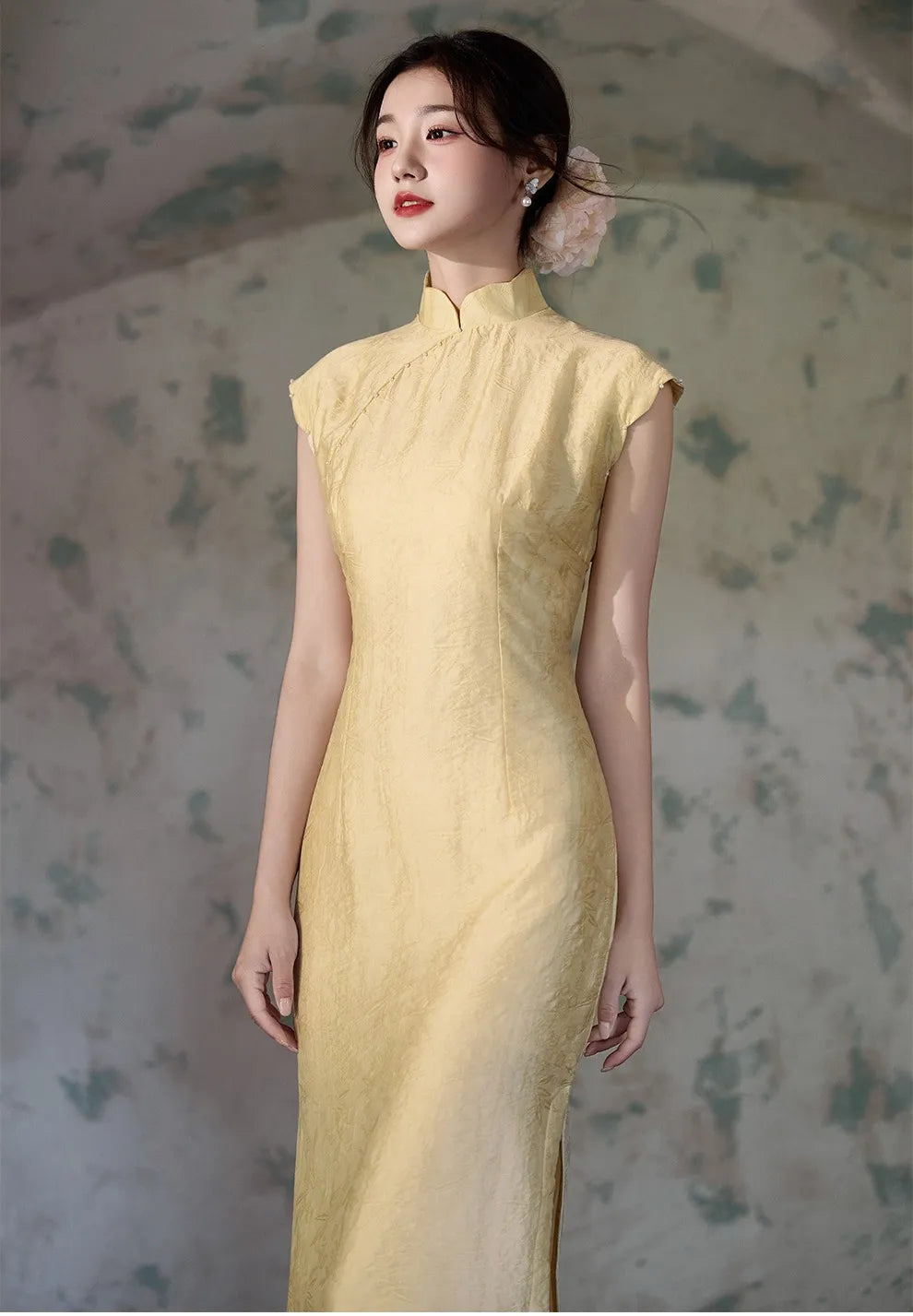 Woman wearing a Yellow Floral Sleeveless Midi Cheongsam Qipao Dress against a textured wall background