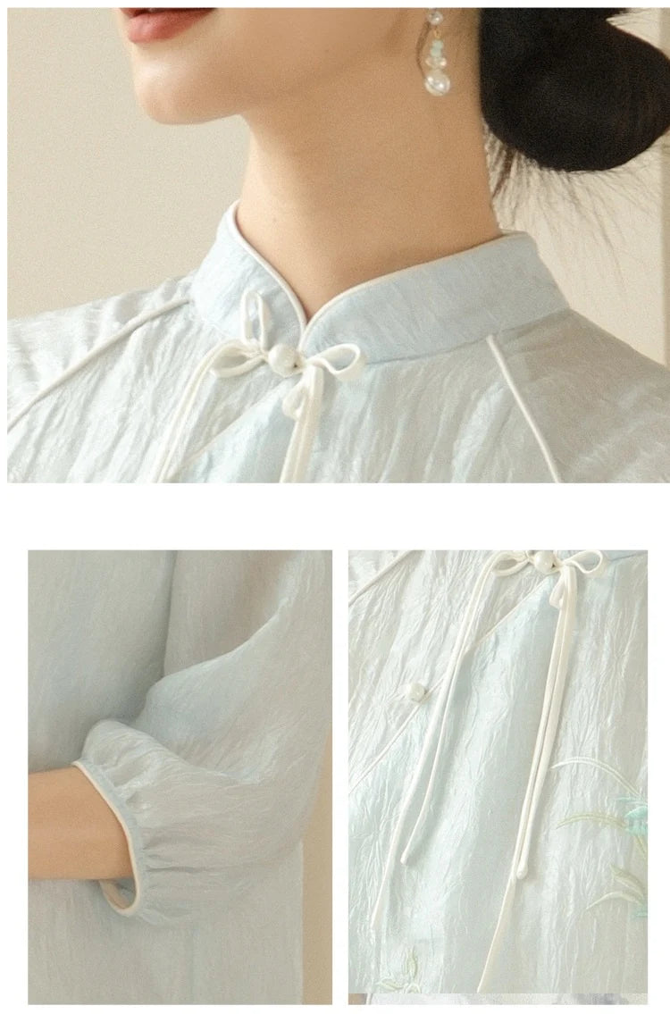 Light blue traditional outfit with white ribbons and pearl earrings on a neutral background