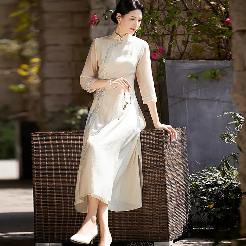 Woman in a beige Modern A-Line Tencel Jacquard Loose Cheongsam Qipao Dress sitting on a wicker chair outdoors.