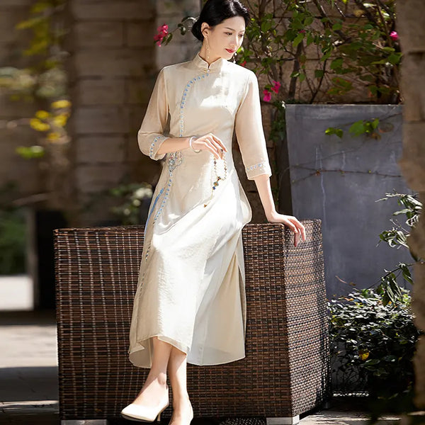 Woman in a beige Modern A-Line Tencel Jacquard Loose Cheongsam Qipao Dress sitting on a wicker chair outdoors.