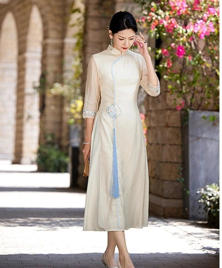 Woman in a beige Modern A-Line Tencel Jacquard Loose Cheongsam Qipao Dress standing outdoors with flowers in the background