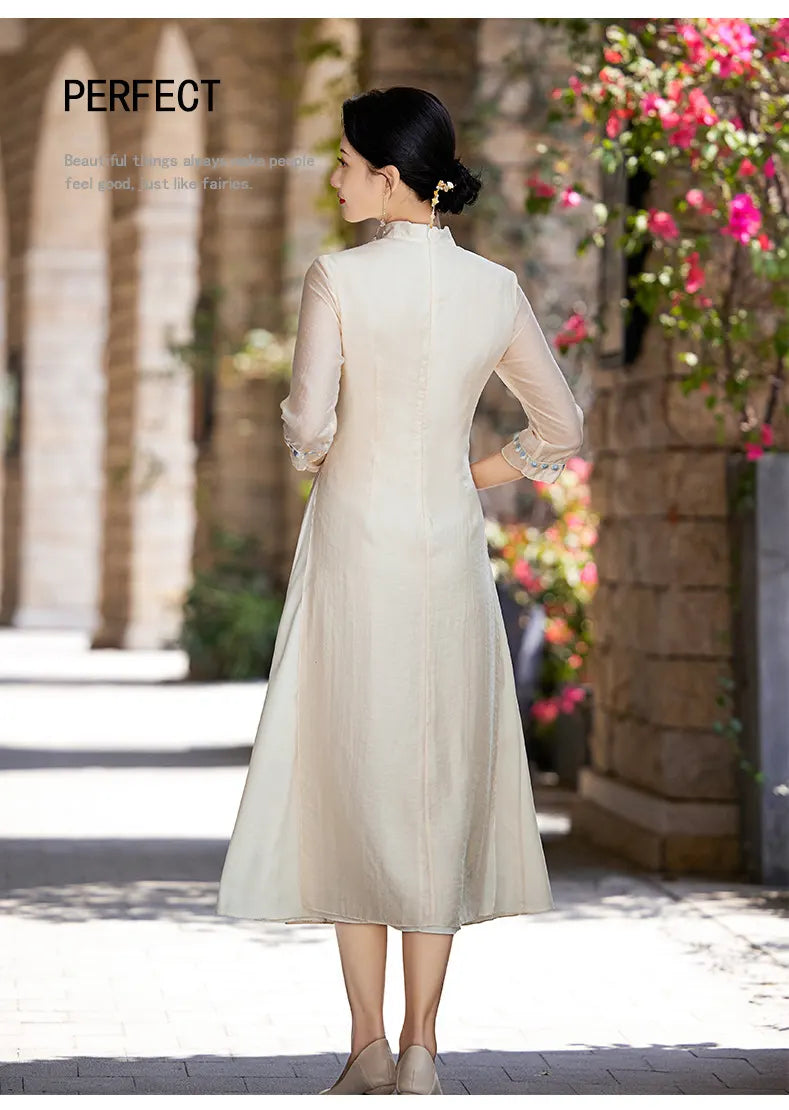A Chinese Woman in a beige Modern A-Line Tencel Jacquard Loose Cheongsam Qipao Dress standing outdoors with flowers in the background