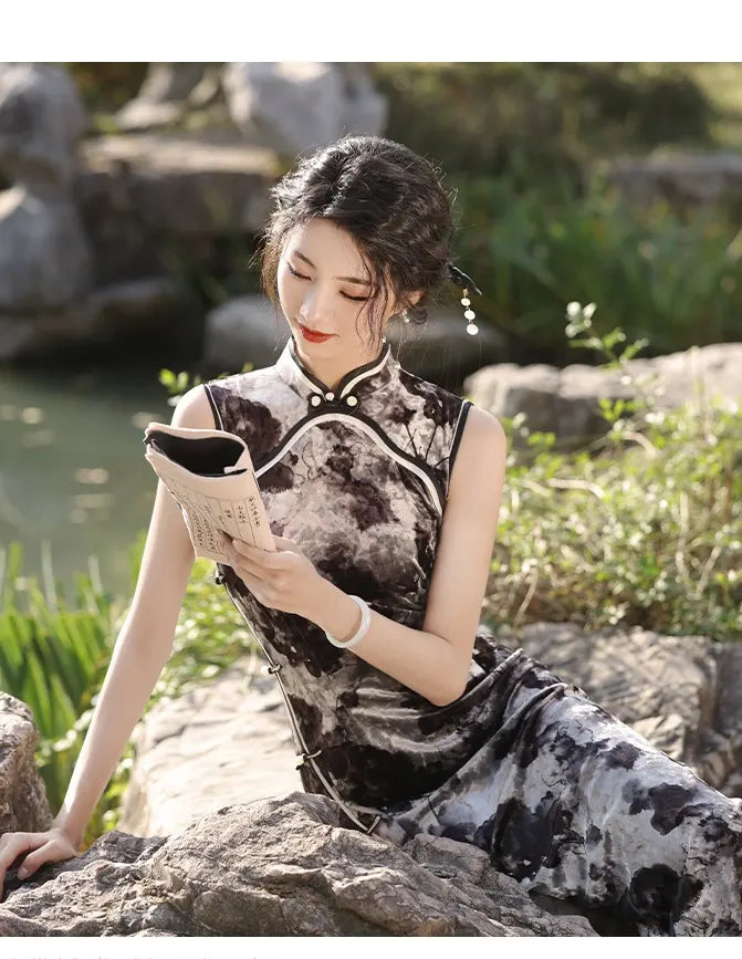 Woman in a traditional black and white Floral Sleeveless Velvet chinese cheongsam Dress  sitting on rocks by a pond.
