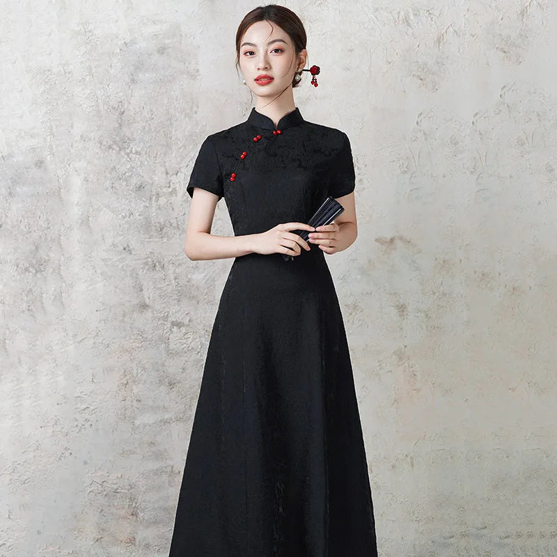 Woman wearing a black  Short Sleeve Floral A Line Qipao cheongsam  with red accents against a gray concrete wall