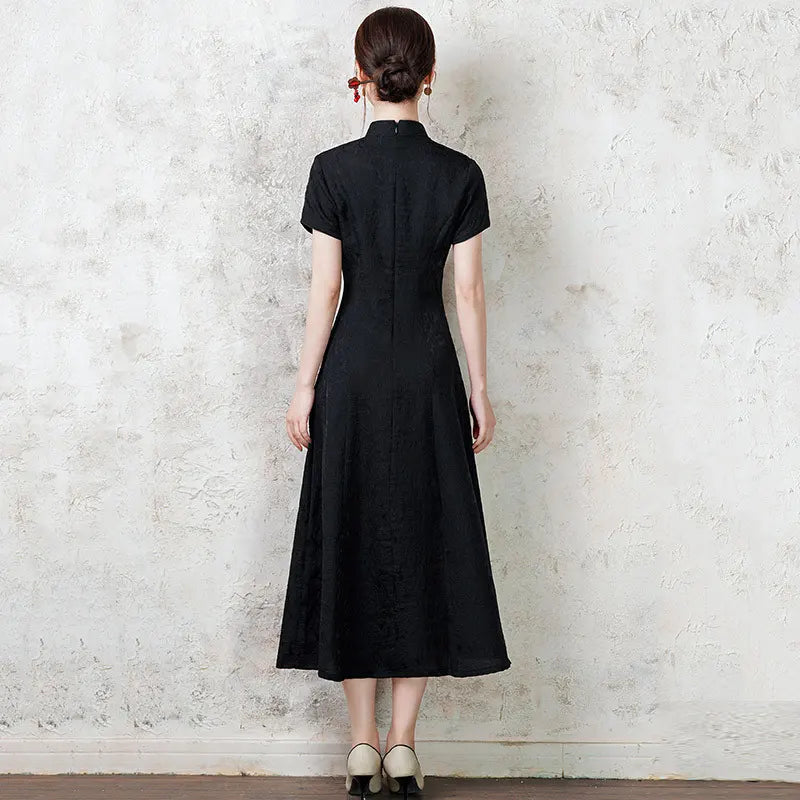 Woman wearing a black  Short Sleeve Floral A Line Qipao cheongsam  dress standing against a textured white wall.