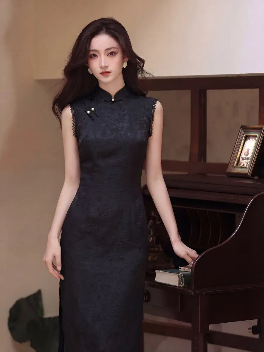 A woman wearing a sleeveless black lace cheongsam-style dress with a high collar and decorative frog buttons standing indoors next to a dark wooden piano.