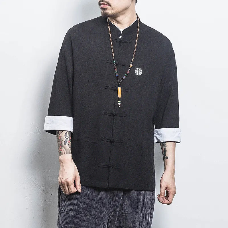 Person wearing a black traditional-style  Three-Quarter Sleeve Zen Heritage Linen-Blend Kong Fu Tang Shirt with white cuffs against a plain background