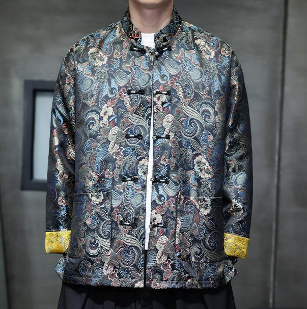 a  traditional Chinese  black Tang jacket made from brocade fabric features a rich, multicolored floral and swirl pattern with metallic accents and yellow cuffs