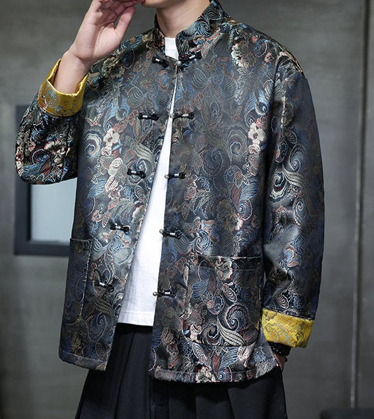 a  traditional Chinese  black Tang jacket made from brocade fabric features a rich, multicolored floral and swirl pattern with metallic accents and yellow cuffs