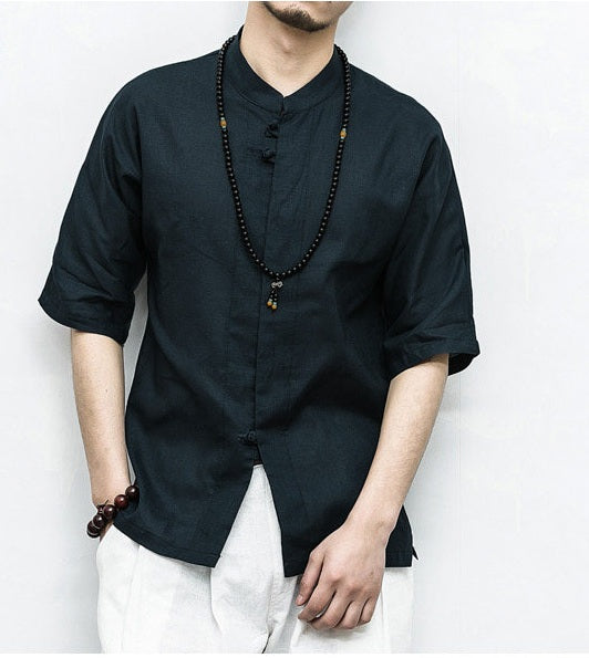 Person wearing a black traditional Men’s Linen Cotton Chinese Mandarin Collar Shirt with white pants against a plain background