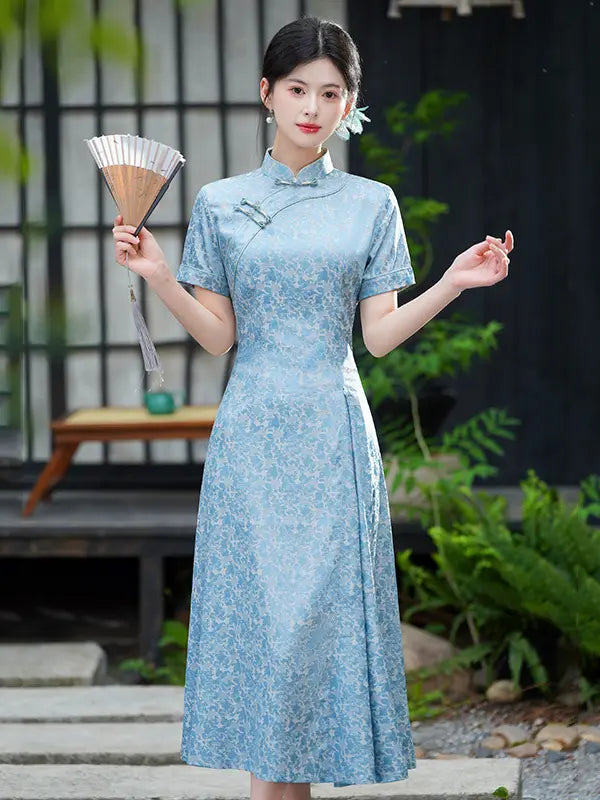Woman in a light blue Modern Floral Short Sleeve A-Line Qipao Dress holding a fan in an outdoor setting.