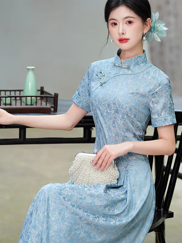 Woman wearing a light blue Modern Floral Short Sleeve A-Line Qipao Dress  holding a clutch in an indoor setting.