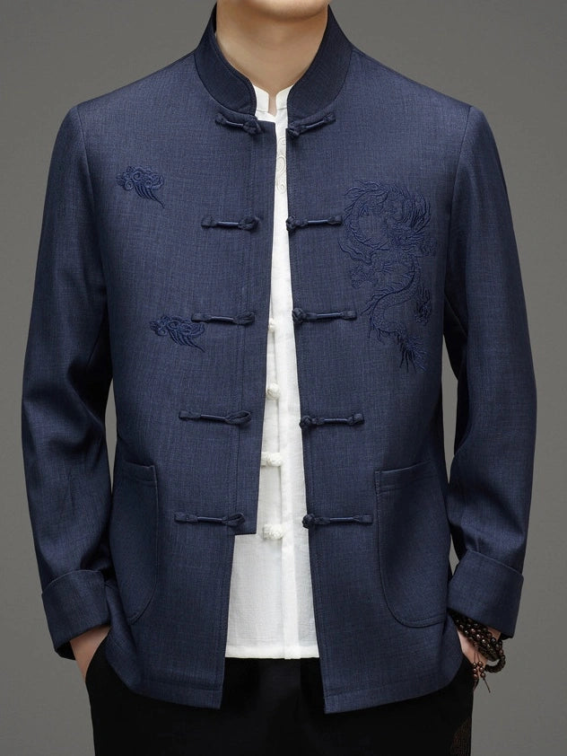 A man wearing a navy blue traditional Chinese-style jacket with dragon embroidery on the chest, paired with a white collared shirt underneath.