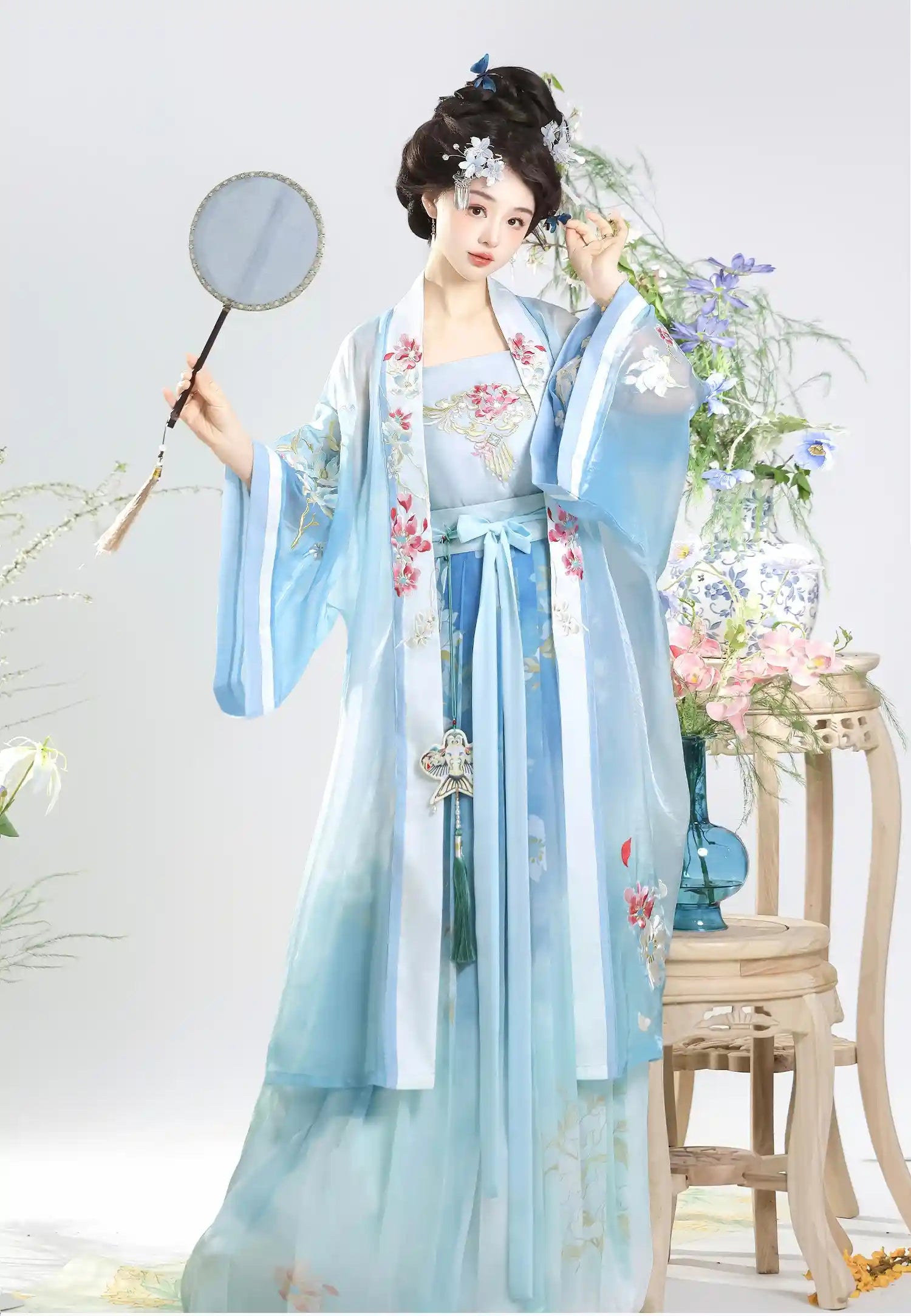 Woman in light blue and white  Traditional Chinese Dress – Elegant Song Dynasty Hanfu Set  holding a fan with floral decorations.