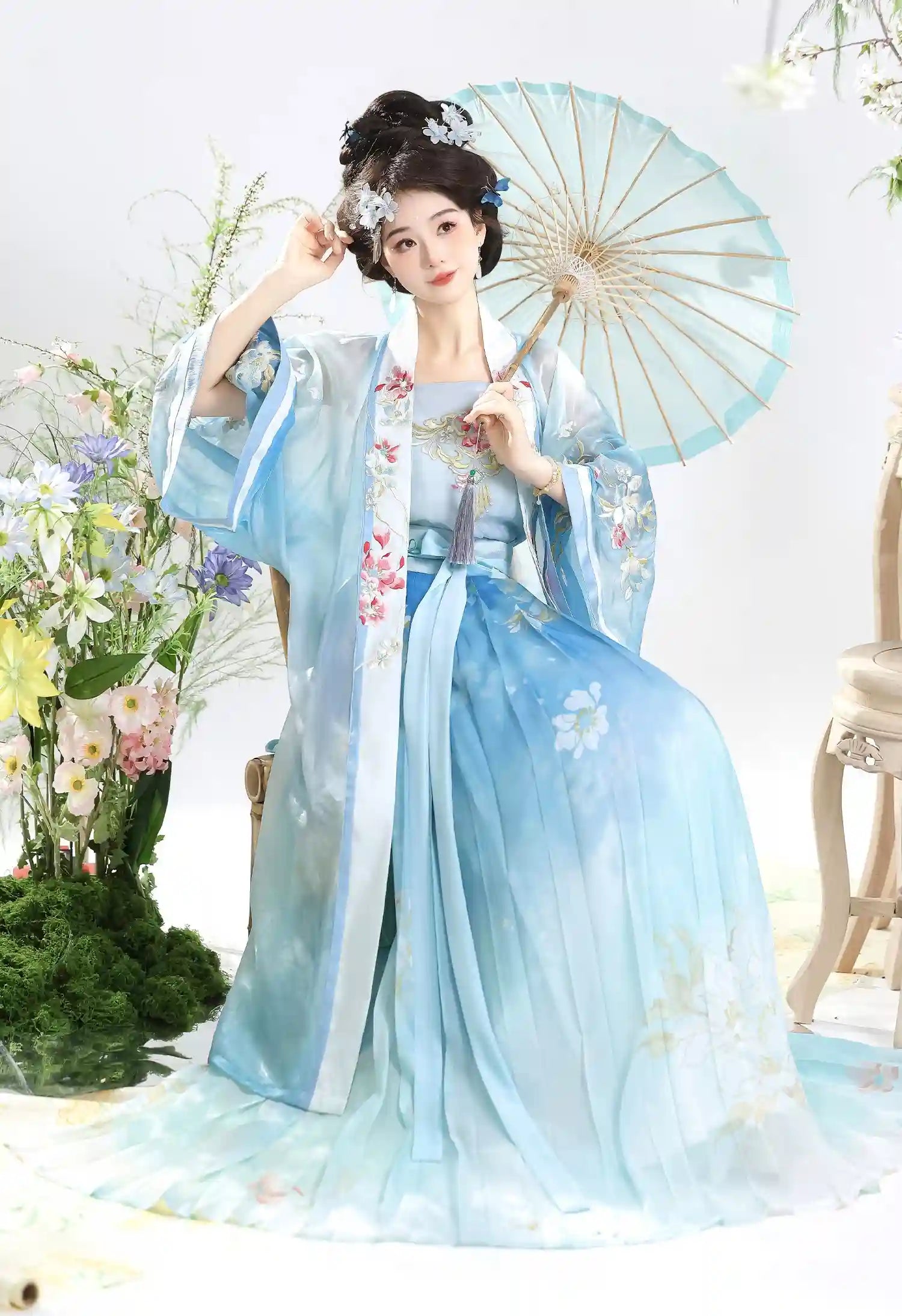 Woman in light blue and white Traditional Chinese Dress – Elegant Song Dynasty Hanfu Set holding a parasol with floral decorations.
