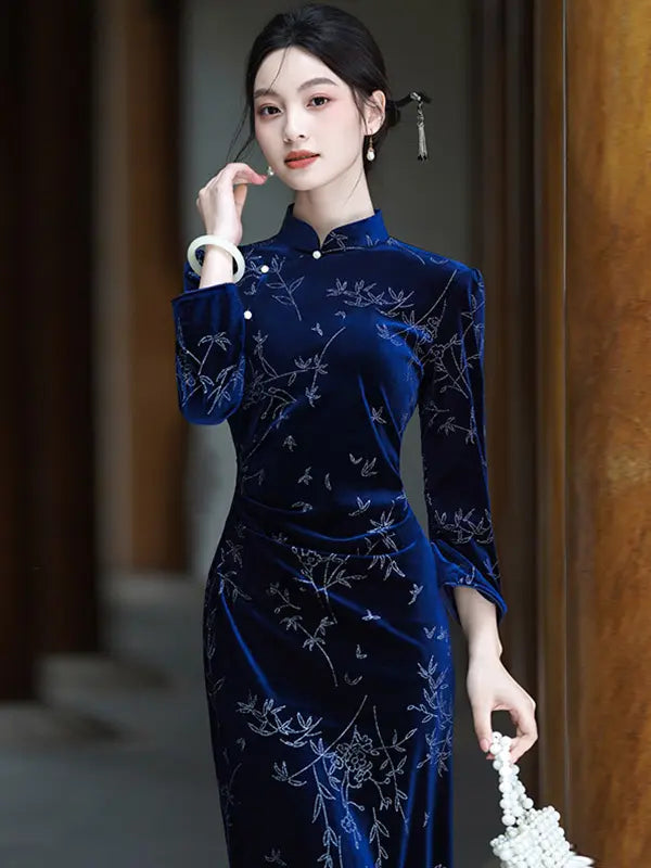 A woman wearing a dark blue Velvet Long Sleeve Qipao cheongsam dress with silver floral embroidery, standing in a corridor with wooden doors.