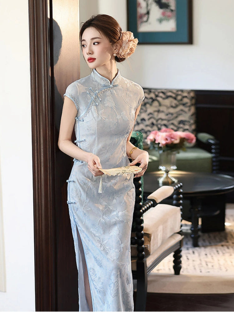 Woman in a light blue traditional  Vintage Floral Burnout Velvet Jacquard Qipao dress standing in a room with decor elements.