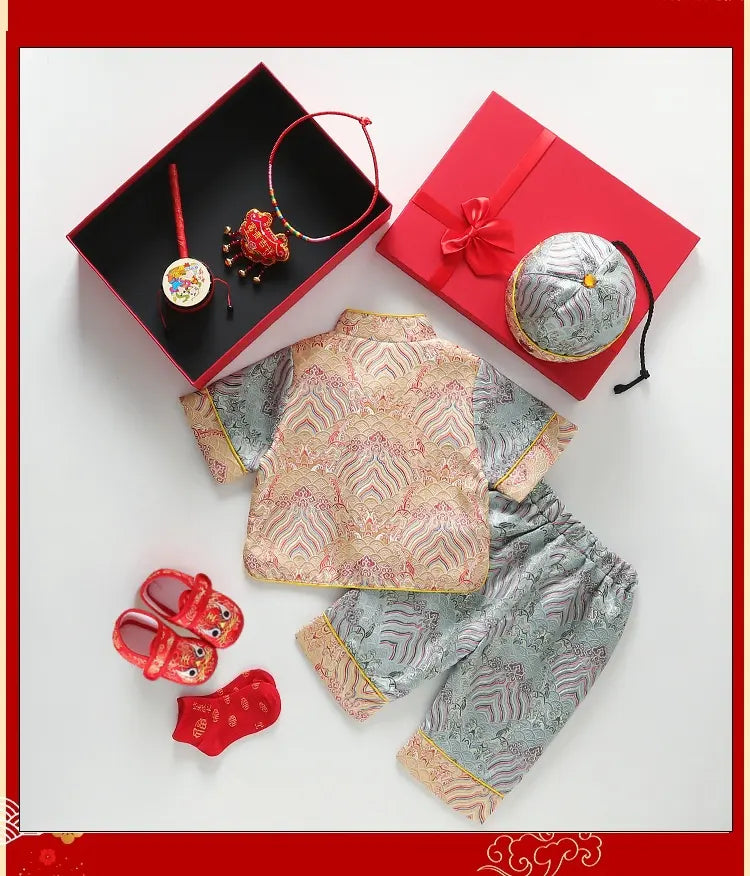 Traditional Chinese baby outfit with shoes, headband, and decorative items on a white background