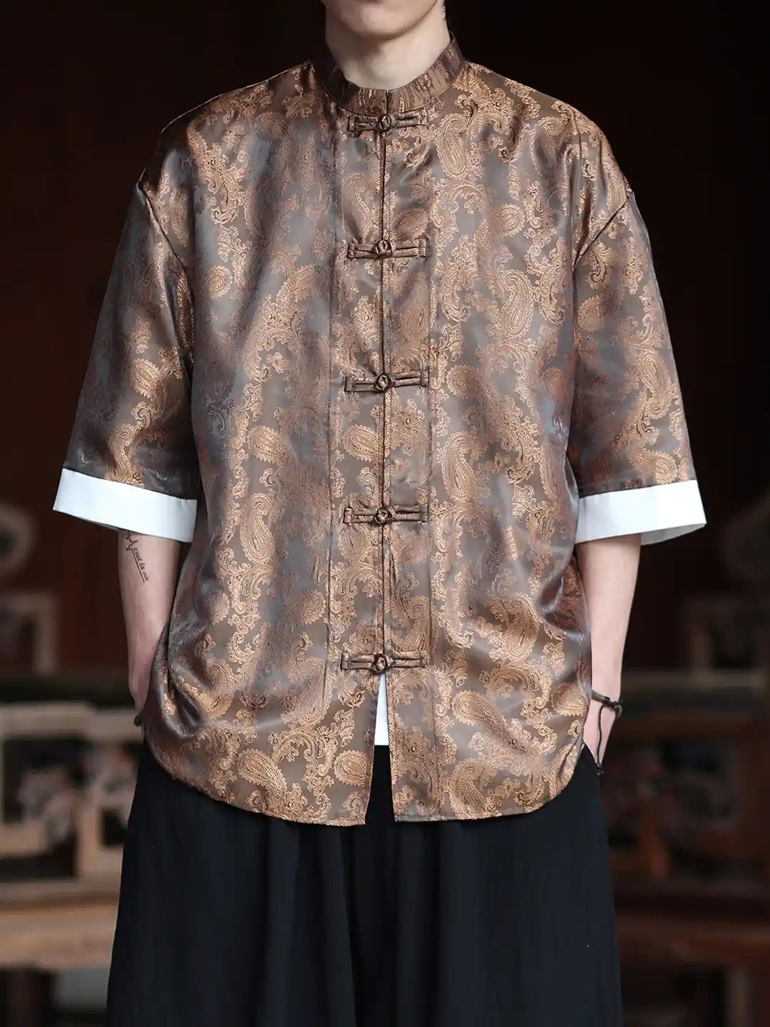 Person wearing a patterned brown Modern New Chinese Style Men's Half Sleeve Jacquard Tang Shirt  with a blurred background