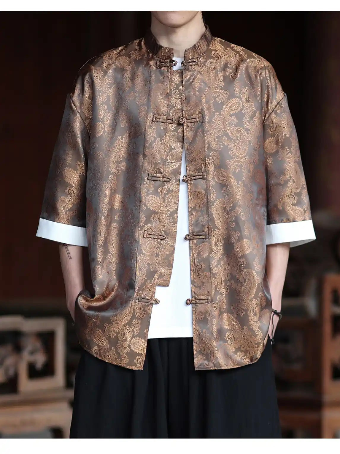 Person wearing a patterned brown Modern New Chinese Style Men's Half Sleeve Jacquard Tang Shirt jacket with white cuffs and collar.