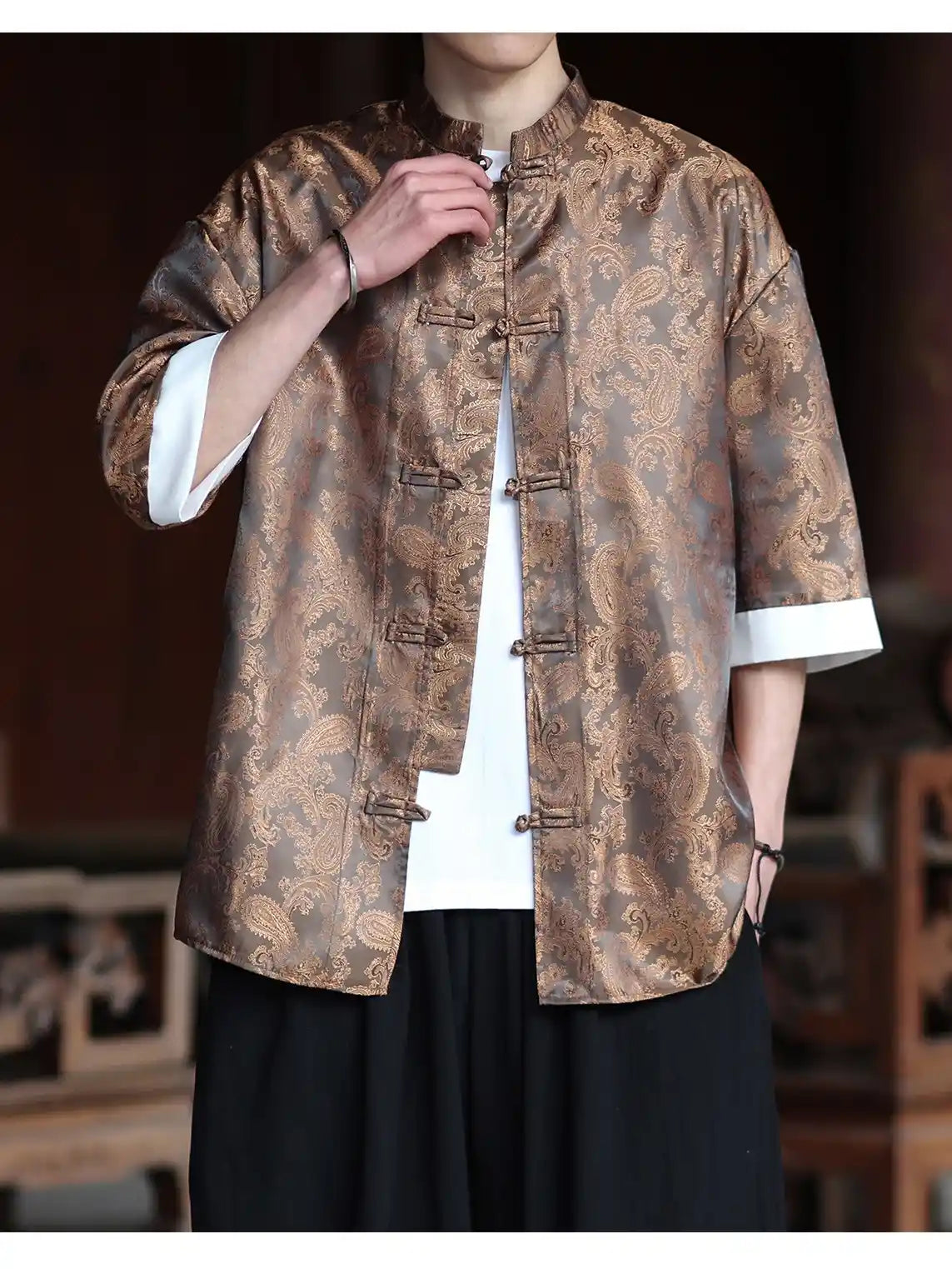Person wearing a traditional patterned  brown Modern New Chinese Style Men's Half Sleeve Jacquard Tang Shirt jacket with a blurred background