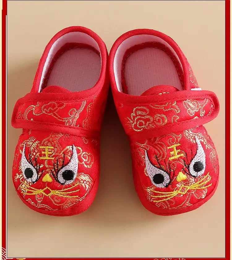 Red embroidered slippers with gold designs on a beige background