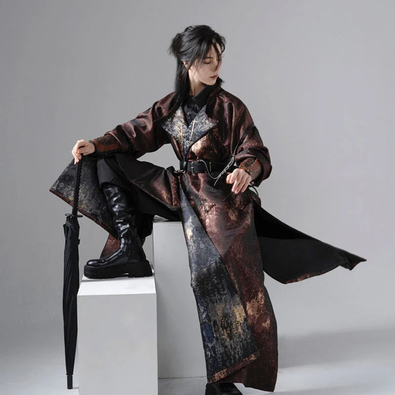 a male wearing a long, darkChinese Reversible Hanfu Robe  sitting on a white cube with a gray background.