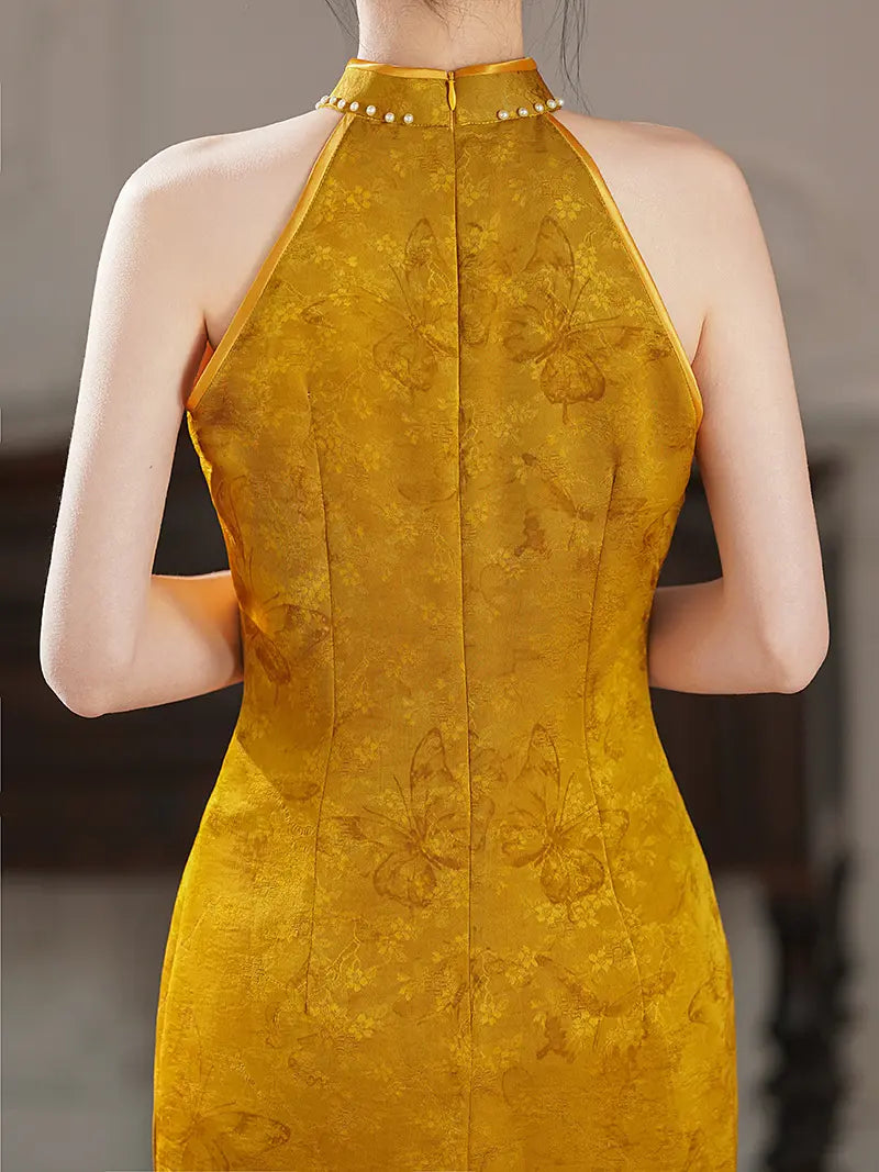 A woman shown from the back wearing a yellow Pearl-Trimmed Sleeveless Halter Jacquard Satin Qipao  dress with a subtle butterfly pattern and a row of small pearl-like embellishments around the neckline.