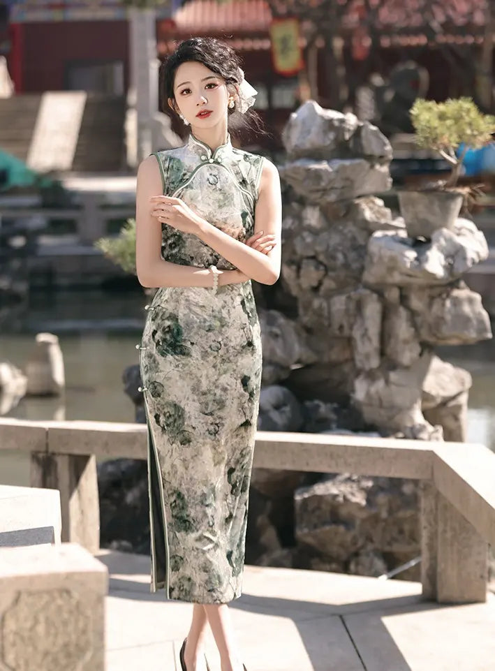 Woman in a green  Floral Sleeveless Velvet Qi pao Dress standing in an outdoor setting with rocks and water.