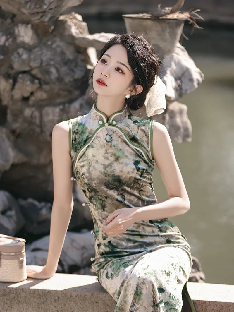 Woman in a traditional green  Floral Sleeveless Velvet Qipao Dress sitting outdoors with stone and water background