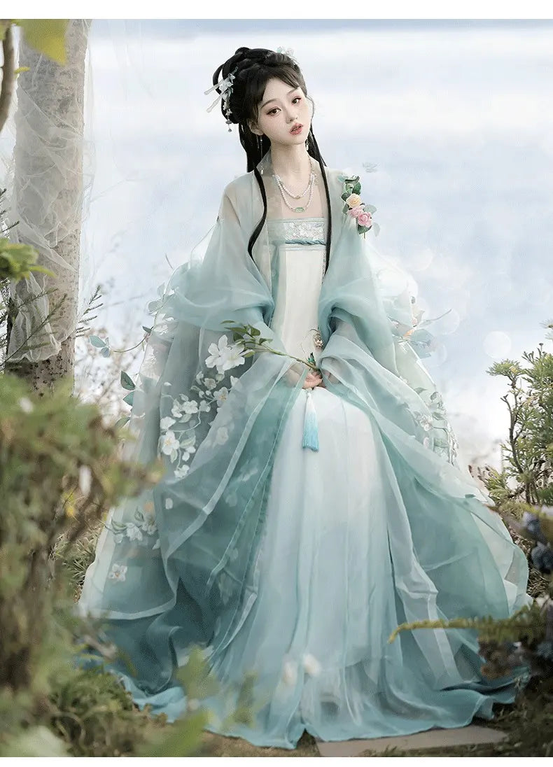 Person in green Floral Traditional Chinese Tang Dynasty Hanfu clothing standing in a natural setting with trees and flowers.