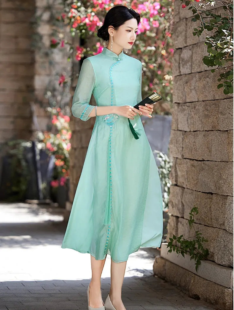 a chinese Woman in a light green Modern A-Line Tencel Jacquard Loose Cheongsam Qipao Dress  standing outdoors with flowers and stone wall in the background