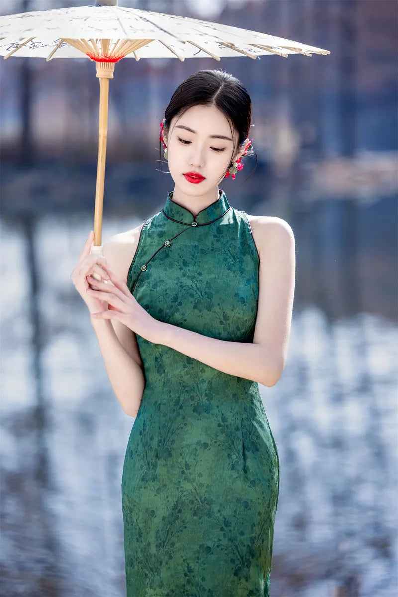 Woman in a green Modern Chinese Mandarin Dress Sleeveless Qipao  holding an umbrella with a blurred background
