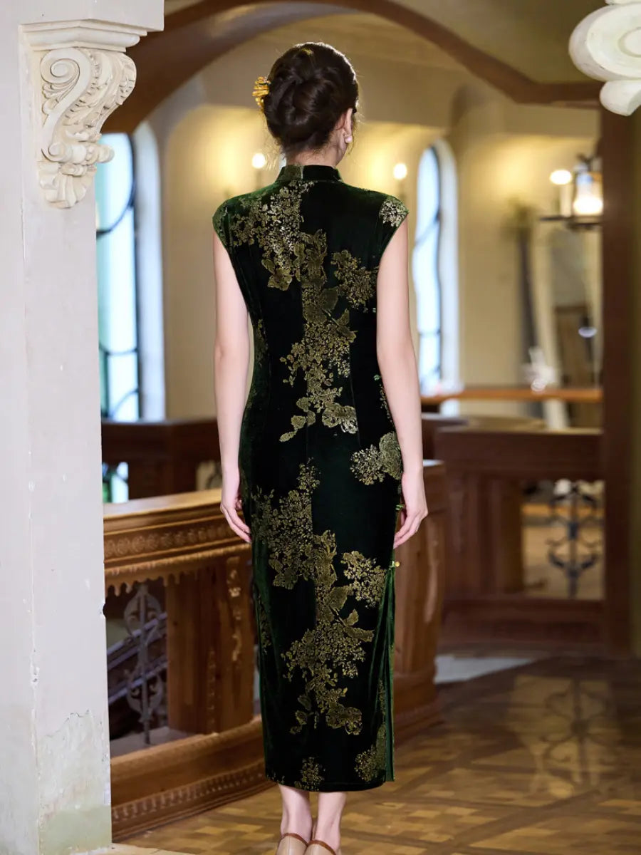 A woman viewed from behind wearing a dark green velvet cheongsam with gold floral embroidery, standing in an elegant indoor setting with wooden railings and warm lighting.
