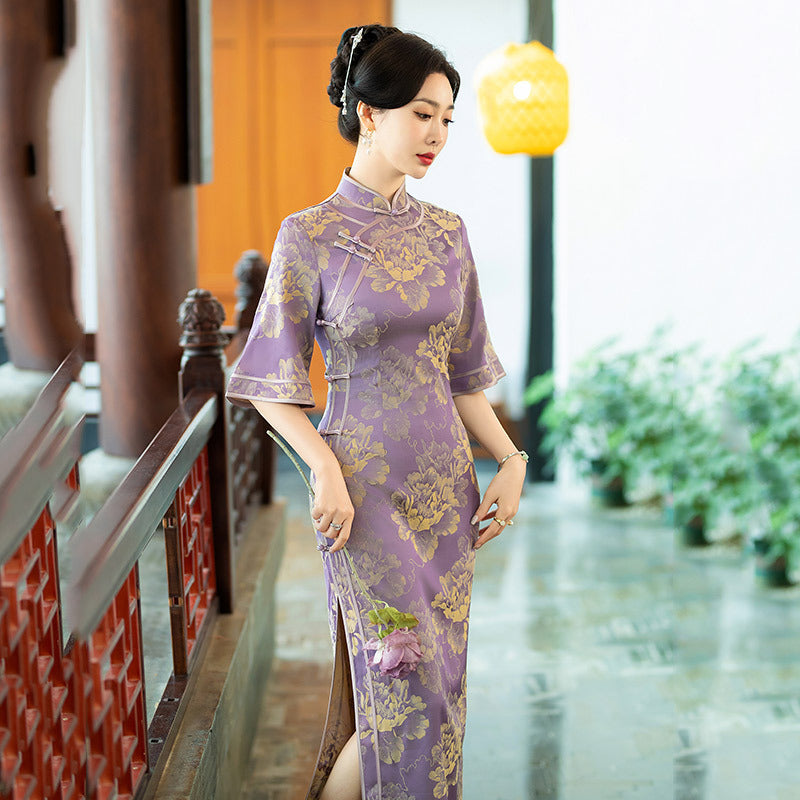 model in half sleevel floral purple qipao cheong dress looking down
