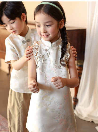 A chinese kid girl in white cheongsam dress and a chinese boy kid in matching white tang jacket smiling